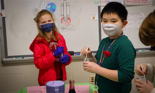 Students smile while holding science experiments